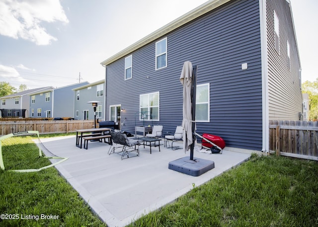 back of property with a lawn, an outdoor living space, a patio area, and fence