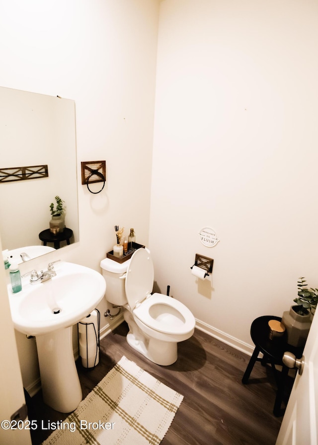 bathroom featuring toilet, wood finished floors, and baseboards