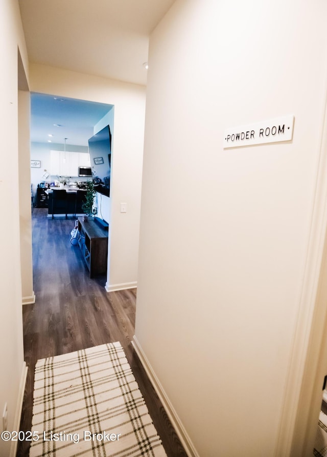 corridor featuring dark wood-style flooring and baseboards