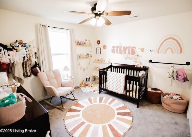 bedroom with a crib, carpet flooring, ceiling fan, and visible vents