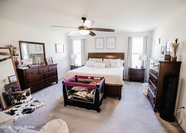 bedroom with ceiling fan, light carpet, and multiple windows