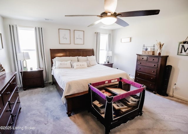 bedroom featuring a ceiling fan, multiple windows, light colored carpet, and visible vents