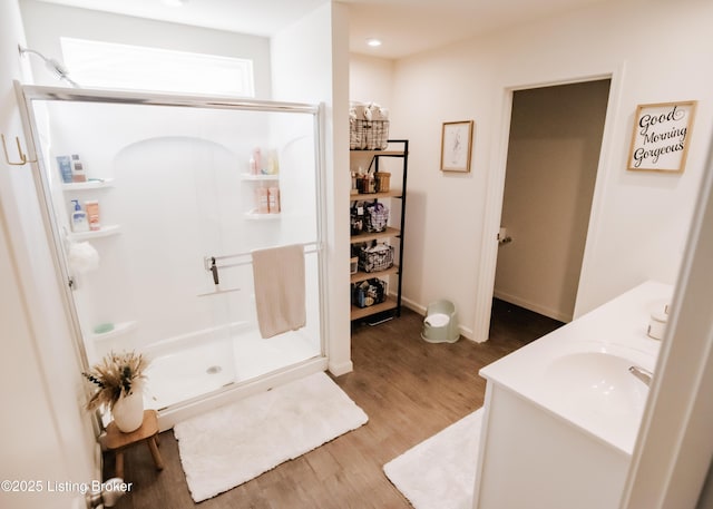 bathroom featuring wood finished floors, baseboards, a stall shower, and a sink
