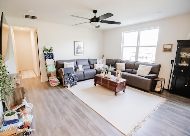 living area with a ceiling fan, visible vents, and wood finished floors