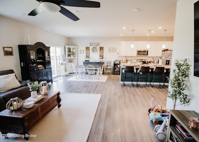 living room featuring recessed lighting, a ceiling fan, and light wood-style floors