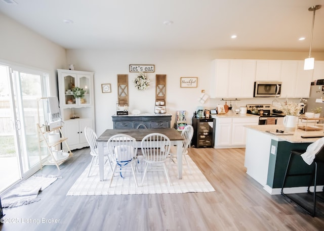 kitchen with light wood-type flooring, white cabinetry, stainless steel appliances, and plenty of natural light