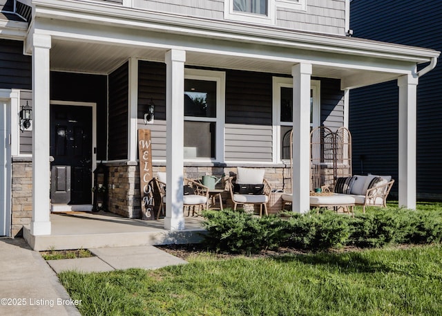 doorway to property featuring a porch and stone siding