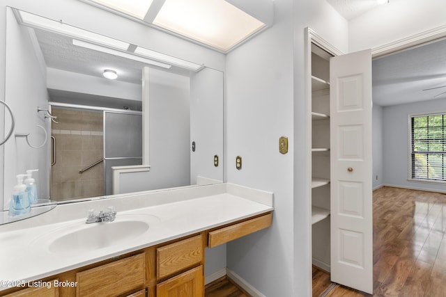 full bathroom featuring vanity, baseboards, wood finished floors, and a tile shower