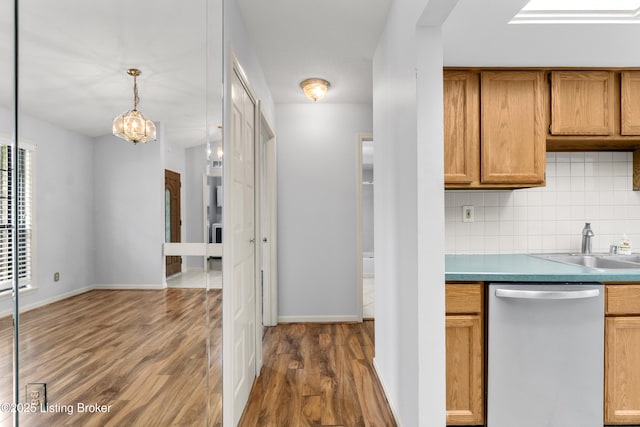 kitchen with an inviting chandelier, wood finished floors, dishwasher, a sink, and backsplash