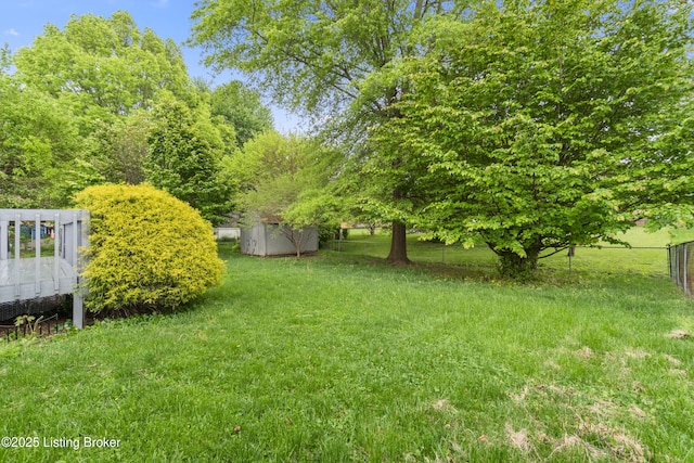 view of yard with fence, an outbuilding, and a storage shed