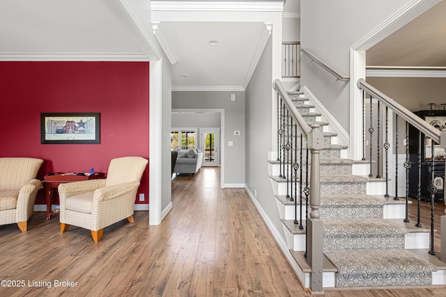 entrance foyer featuring baseboards, ornamental molding, stairs, and wood finished floors