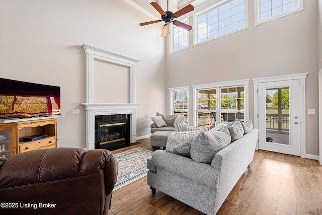 living area with wood-type flooring, a ceiling fan, and a towering ceiling