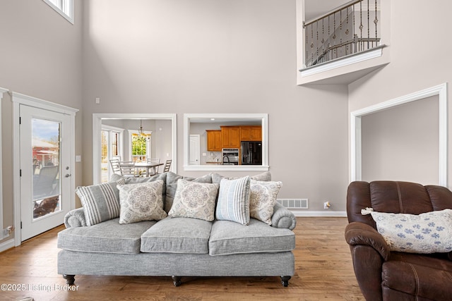 living room with plenty of natural light, visible vents, and a towering ceiling