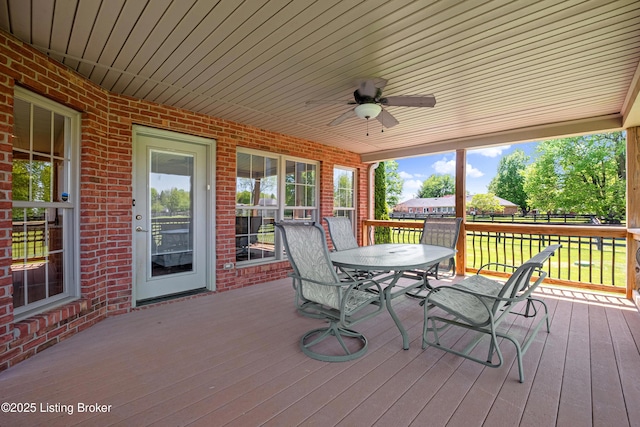 wooden terrace with fence, a ceiling fan, and outdoor dining space