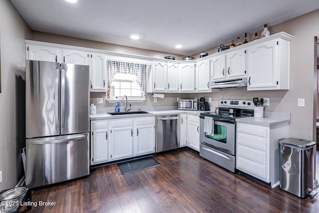 kitchen with stainless steel appliances, a sink, under cabinet range hood, white cabinetry, and light countertops