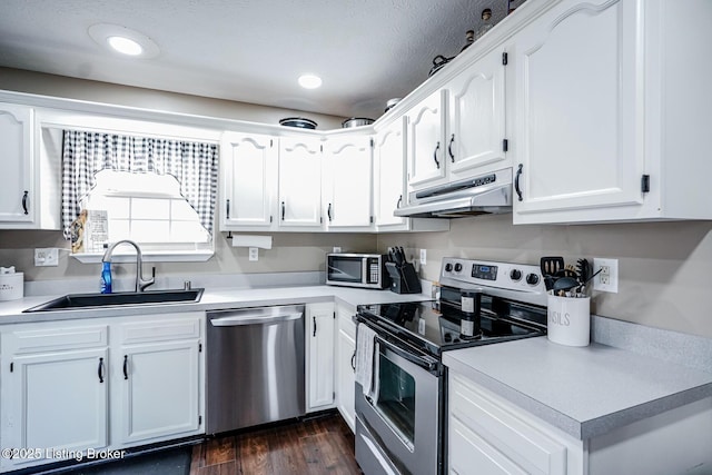 kitchen featuring appliances with stainless steel finishes, under cabinet range hood, a sink, light countertops, and white cabinetry