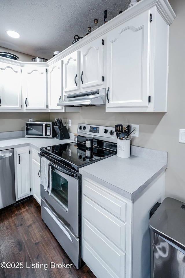 kitchen with stainless steel appliances, under cabinet range hood, light countertops, white cabinetry, and dark wood-type flooring