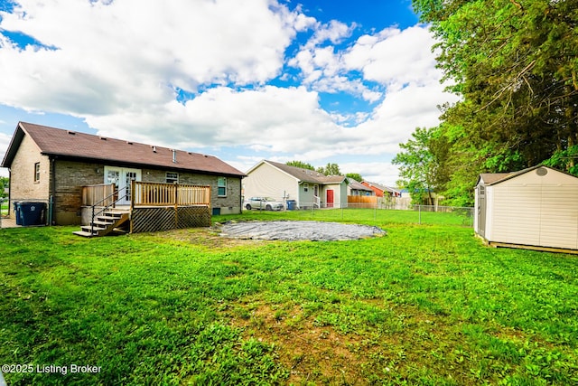 view of yard with a wooden deck, a storage shed, an outbuilding, and french doors