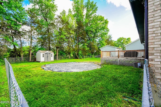 view of yard featuring a shed, an outbuilding, a wooden deck, and central AC