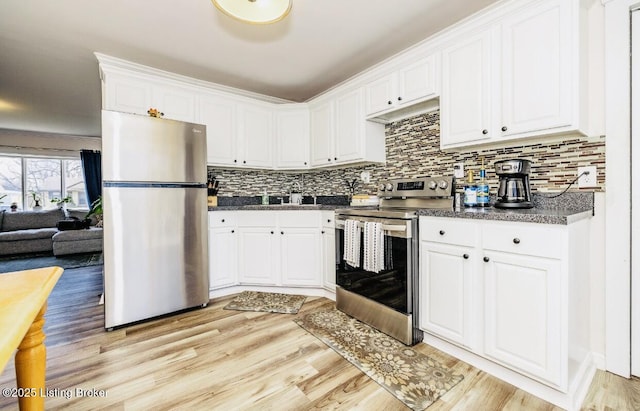 kitchen featuring white cabinetry, decorative backsplash, a sink, stainless steel appliances, and light wood-type flooring