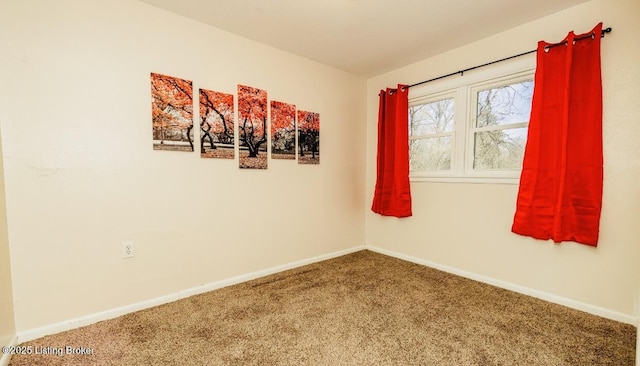 spare room featuring carpet and baseboards