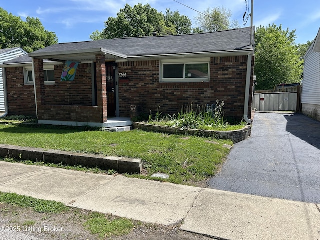 bungalow-style home featuring brick siding, roof with shingles, and a front lawn