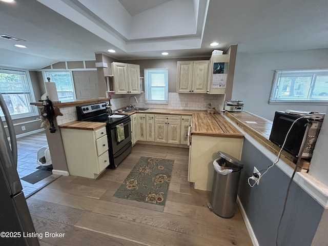 kitchen featuring visible vents, stainless steel electric range oven, tasteful backsplash, a peninsula, and butcher block counters