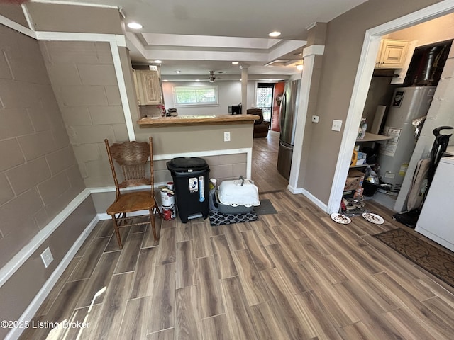 living area with wood finished floors, baseboards, recessed lighting, gas water heater, and a ceiling fan