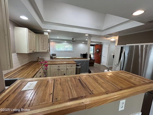 kitchen featuring decorative backsplash, a peninsula, ceiling fan, recessed lighting, and wood counters