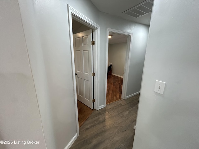 corridor featuring dark wood-style flooring, baseboards, and visible vents