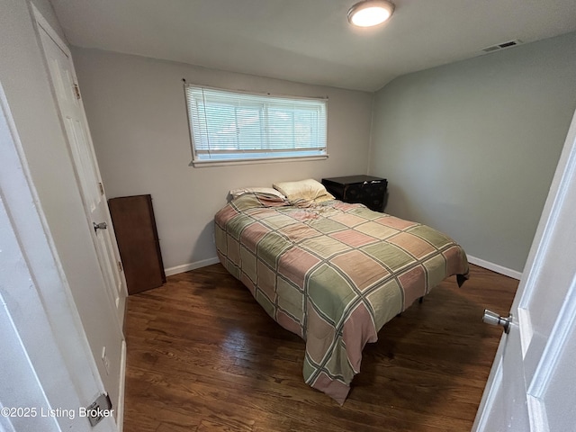 bedroom with baseboards, dark wood finished floors, and visible vents