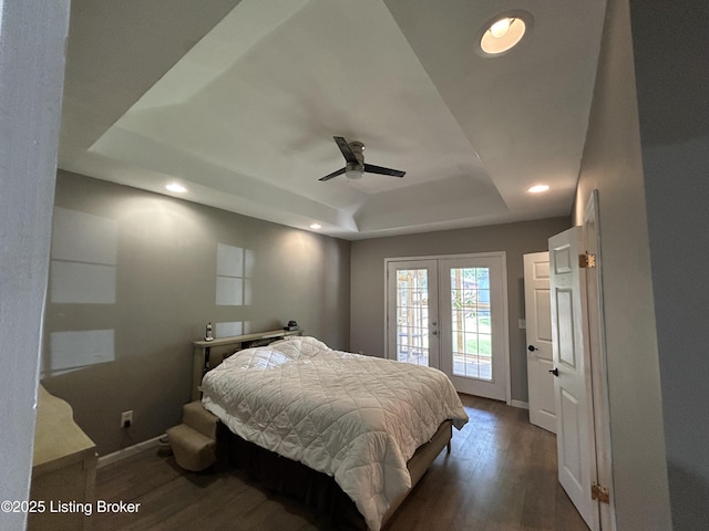 bedroom featuring access to exterior, french doors, baseboards, wood finished floors, and a tray ceiling