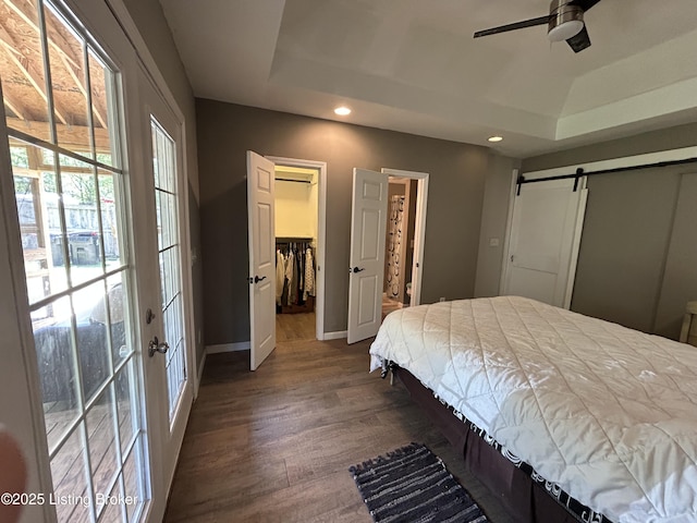 bedroom featuring recessed lighting, a barn door, wood finished floors, and a raised ceiling