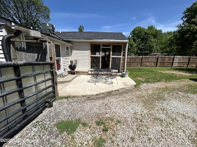 rear view of property featuring a patio, fence, and a shingled roof