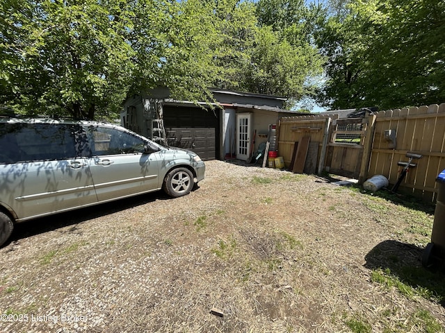 view of yard with an attached garage, fence, and dirt driveway