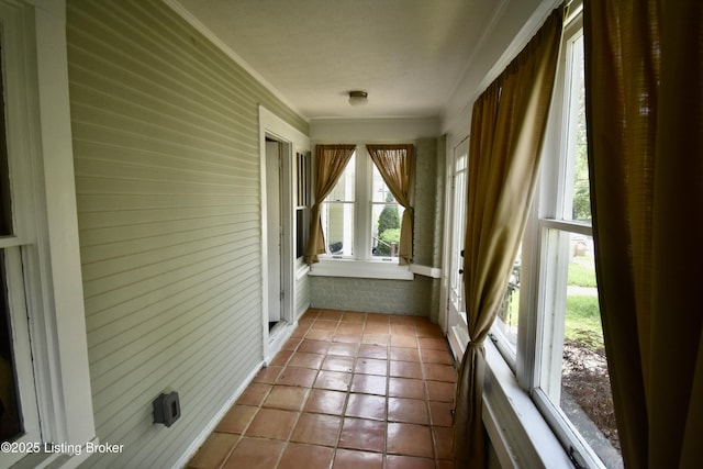 unfurnished sunroom featuring tile patterned flooring and wood walls
