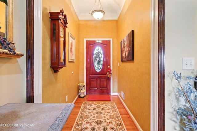 entrance foyer with ornamental molding, light wood-style floors, and baseboards