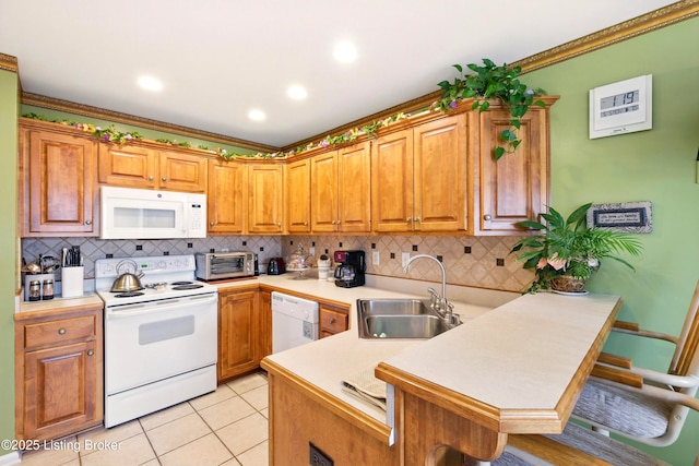 kitchen with white appliances, a sink, a peninsula, light countertops, and ornamental molding