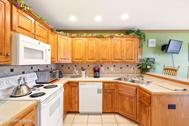 kitchen featuring white appliances, a sink, light countertops, a peninsula, and decorative backsplash