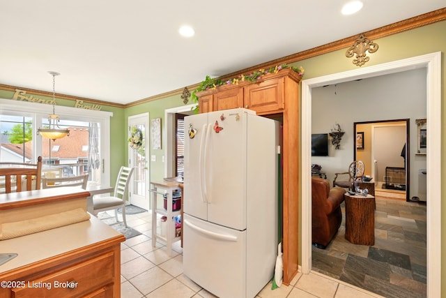 kitchen with freestanding refrigerator, ornamental molding, light tile patterned floors, decorative light fixtures, and light countertops