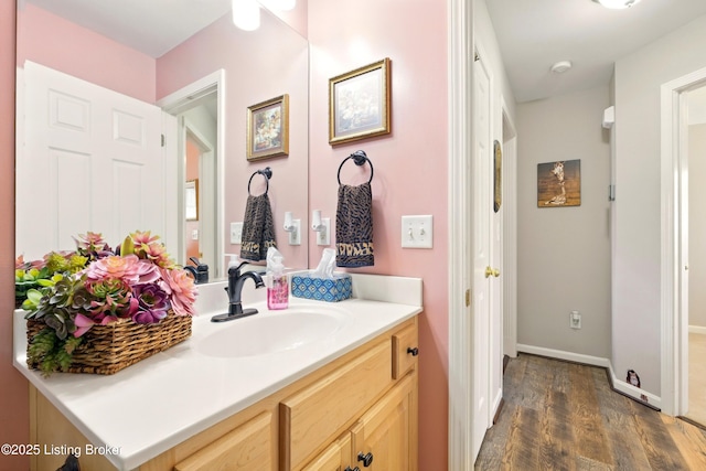 bathroom with wood finished floors, vanity, and baseboards
