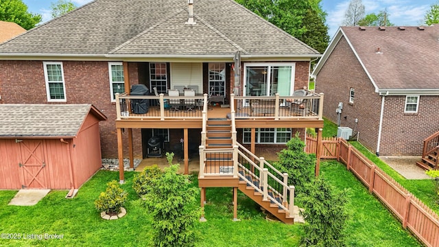 back of house featuring stairway, a shingled roof, a wooden deck, and an outbuilding