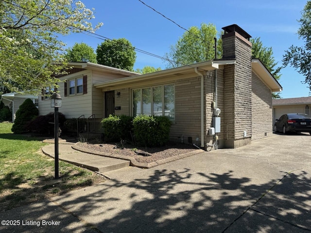 exterior space with a garage, a chimney, and driveway