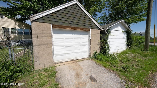 detached garage featuring driveway and fence