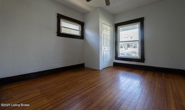 empty room featuring ceiling fan, baseboards, and dark wood finished floors