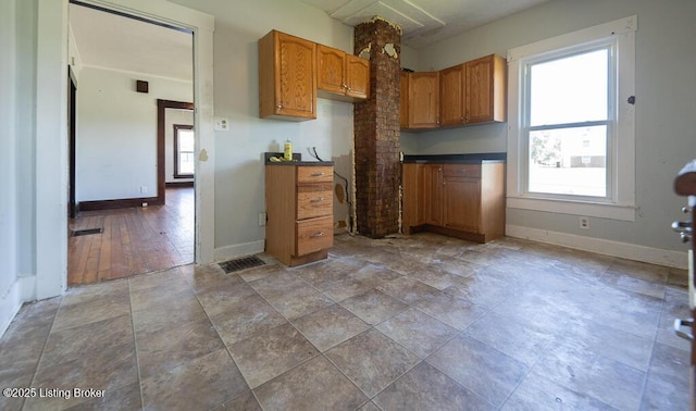 kitchen with baseboards, brown cabinetry, and dark countertops