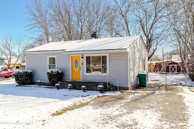 bungalow-style house with a storage shed, an outbuilding, and a chimney