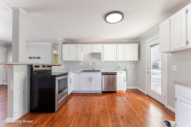 kitchen featuring appliances with stainless steel finishes, ornamental molding, and wood-type flooring