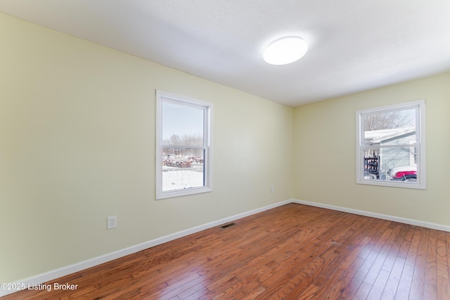 empty room featuring visible vents, baseboards, and hardwood / wood-style floors