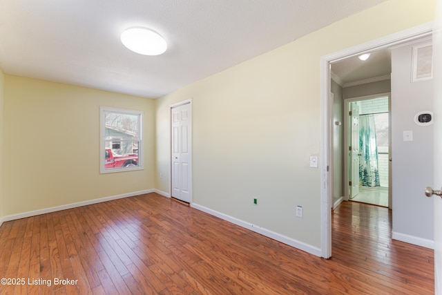 spare room featuring a healthy amount of sunlight, baseboards, and hardwood / wood-style floors